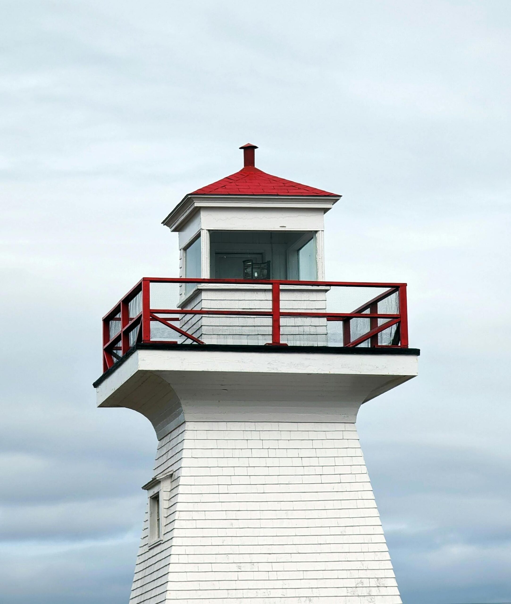 white, wooden lighthouse against cloudy sky